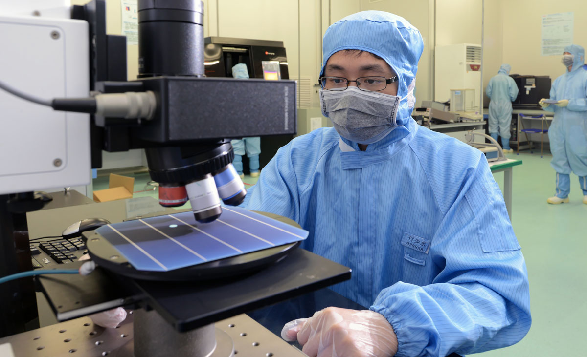 A scientist examines solar panels under specialised testing equipment in a laboratory.