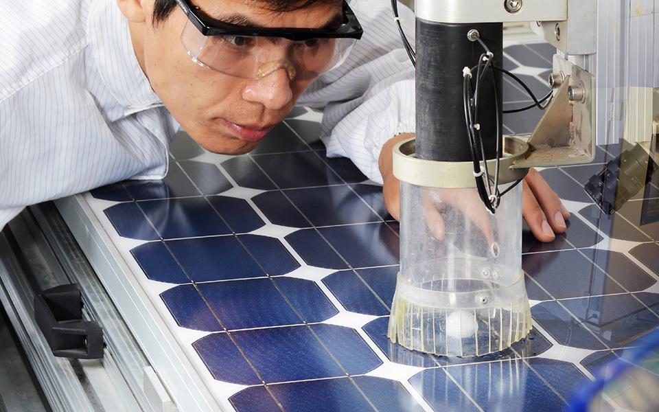 Scientist wearing goggles looks at lab equipment over solar cells