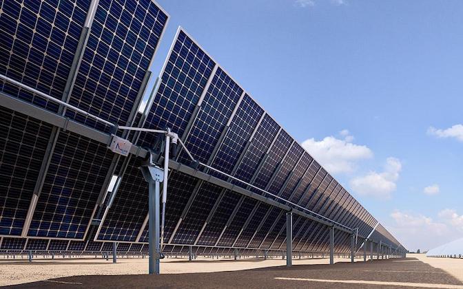 View from below a solar panel installation showing groundmounts with trackers and blue sky in background